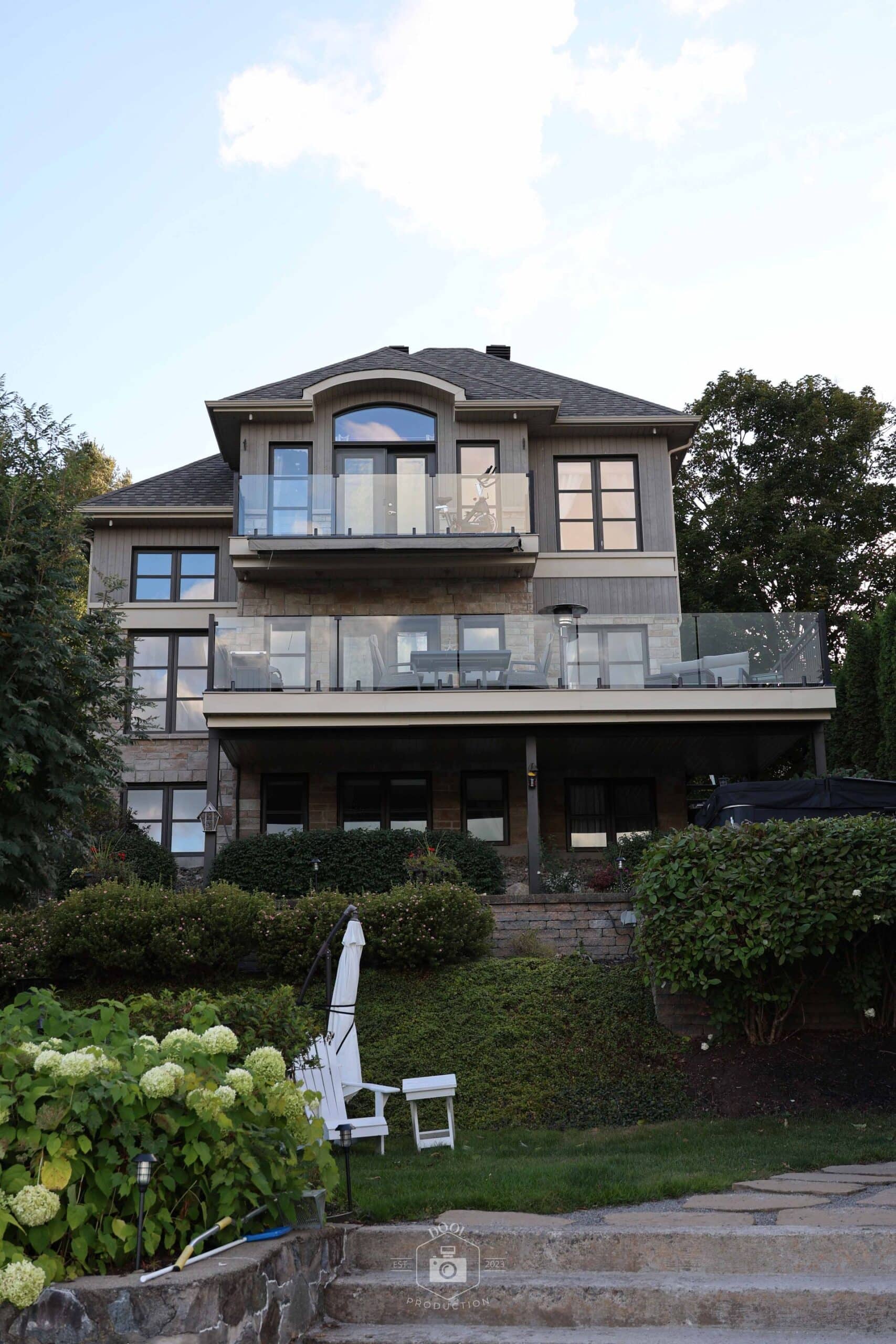 Maison contemporaine avec balcons en verre et revêtement de pierre construite par LUXEM Construction sur la Rive-Nord.